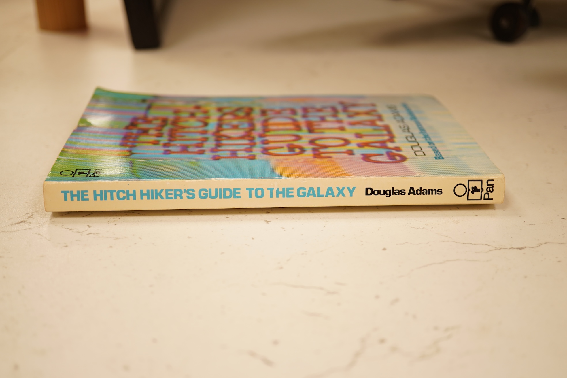 Adams, Douglas - The Hitch Hiker's Guide to the Galaxy. first edition, 2nd printing. half title/radio series leaf; paperback, sm. 8vo. Pan Books, 1979. *published same year as first and with a differently designed cover;